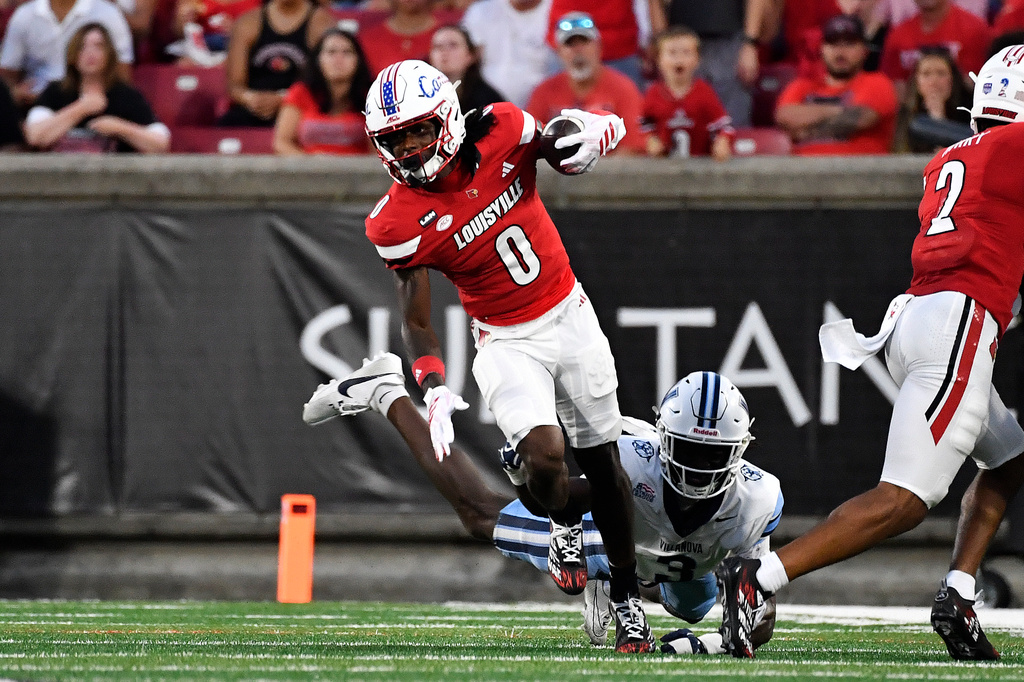 Louisville wide receiver Tre Richardson (0) escapes the table attempt by Villanova defensive back Josh Oluremi (3) during the firsthalf of an NCAA college football game in Louisville, Ky., Friday, Sept. 11, 2026. (AP Photo/Timothy D. Easley)