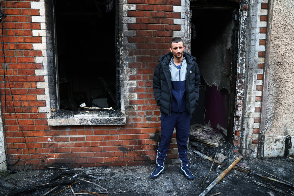Jamie Corrie stands beside his burnt out house after rioting broke out late Tuesday, in east Belfast, Northern Ireland, Wednesday, June 10, 2026, following a stabbing incident. (AP Photo/Peter Morrison)