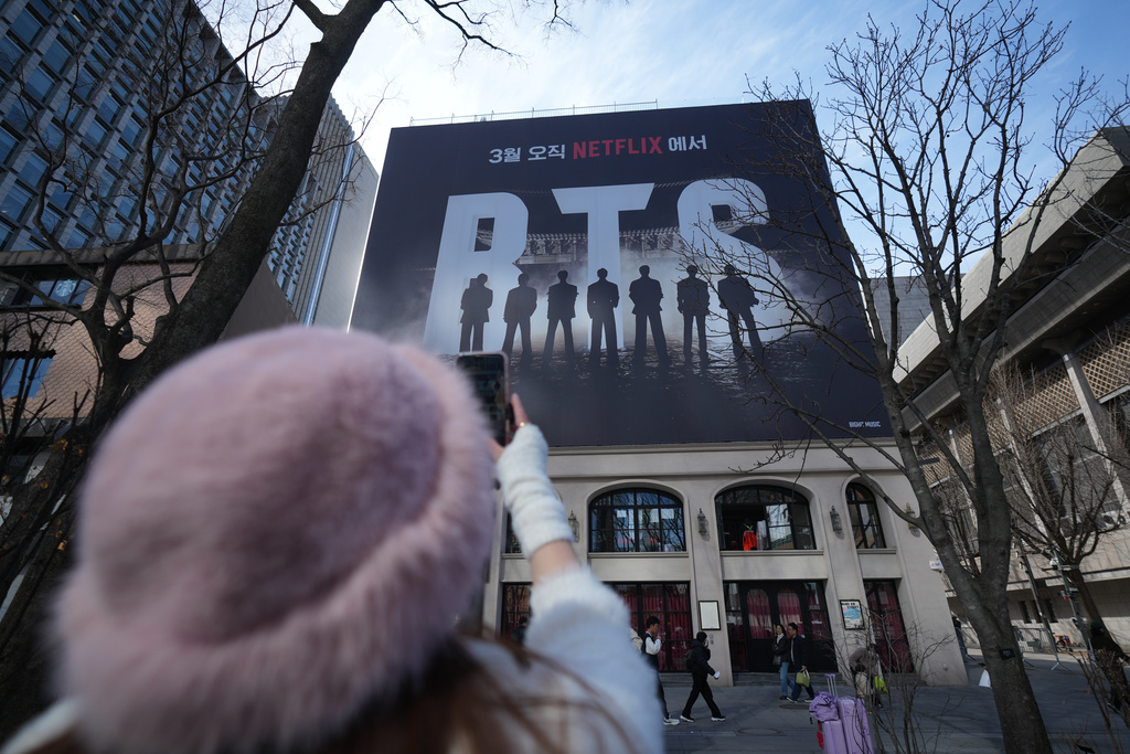 A fan of K-pop band BTS films billboard showing of BTS in downtown Seoul, South Korea, Thursday, March 19, 2026. (AP Photo/Lee Jin-man)