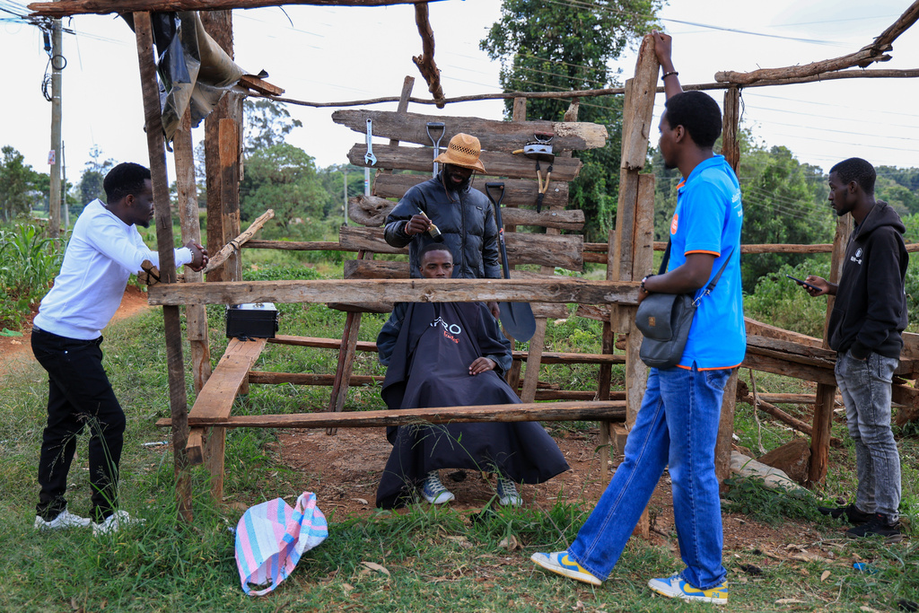 Barber and content creator Safari Martins shaves Ian Njenga in Kiambu, Kenya, Wednesday, Nov. 26, 2025. (AP Photo/Andrew Kasuku)