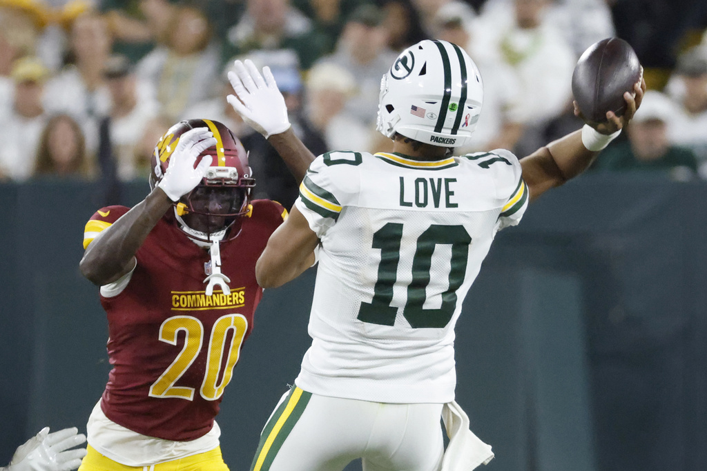 Green Bay Packers quarterback Jordan Love (10) throws under pressure from Washington Commanders safety Quan Martin (20) during the second half of an NFL football game Thursday, Sept. 11, 2025, in Green Bay, Wis. (AP Photo/Mike Roemer)