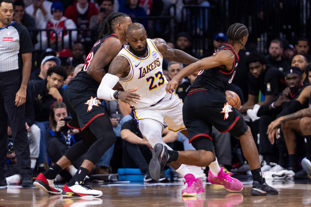 Los Angeles Lakers' LeBron James, center, gets the ball stolen by Philadelphia 76ers' Tyrese Maxey, right, as Jabari Walker, left, is defending during the second half of an NBA basketball game, Sunday, Dec. 7, 2025, in Philadelphia. (AP Photo/Chris Szagola)