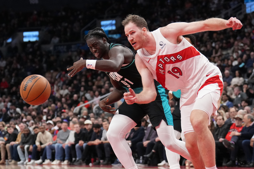 Toronto Raptors center Jakob Poeltl (19)and Portland Trail Blazers guard Sidy Cissoko (91) battle for the loose ball during second half NBA basketball action in Toronto on Tuesday, Dec. 2, 2025. (Nathan Denette/The Canadian Press via AP)