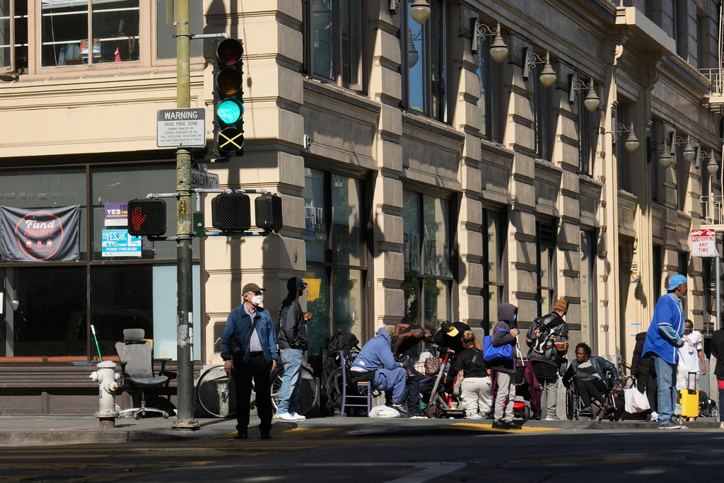 People converge on a street corner in the Tenderloin District on Tuesday, Oct. 21, 2025, in San Francisco. (AP Photo/Jeff Chiu)