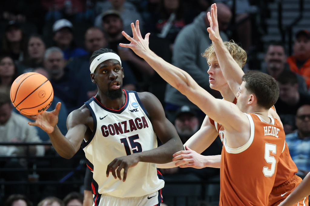 Gonzaga forward Graham Ike (15) passes the ball under pressure from Texas forward Camden Heide (5) during the first half in the second round of the NCAA college basketball tournament Saturday, March 21, 2026, in Portland, Ore. (AP Photo/Craig Mitchelldyer)