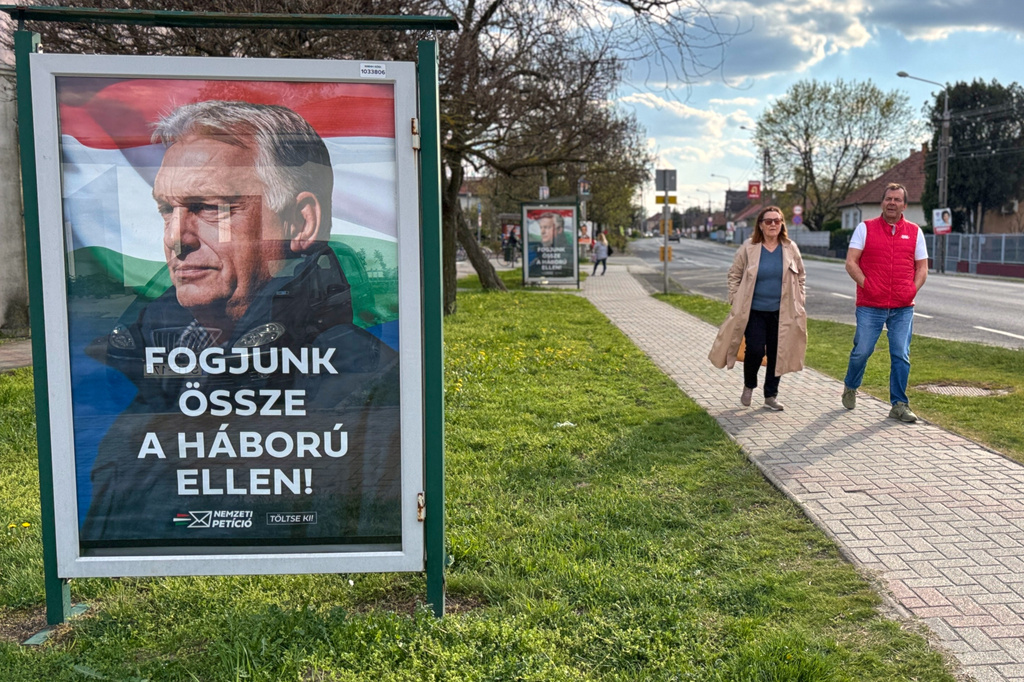 People walk by an electoral poster showing Hungarian Prime Minister Viktor Orban and the slogan "Let's stand together against the war!" in Albertirsa, Hungary, Thursday, April 9, 2026. (AP Photo/Eldar Emric)