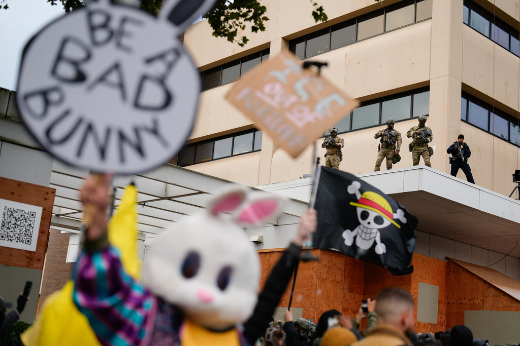 Law enforcement officers watch from the ledge of a U.S. Immigration and Customs Enforcement facility as people protest on Saturday, Oct. 11, 2025, in Portland, Ore. (AP Photo/Jenny Kane)