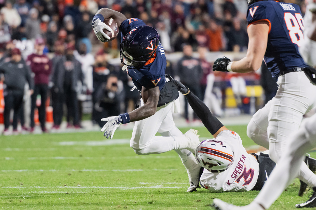 Virginia quarterback Chandler Morris, left, is tackled by Virginia Tech linebacker Kaleb Spencer (3) during the first half of an NCAA college football game Saturday, Nov. 29, 2025, in Charlottesville, Va. (AP Photo/Robert Simmons)
