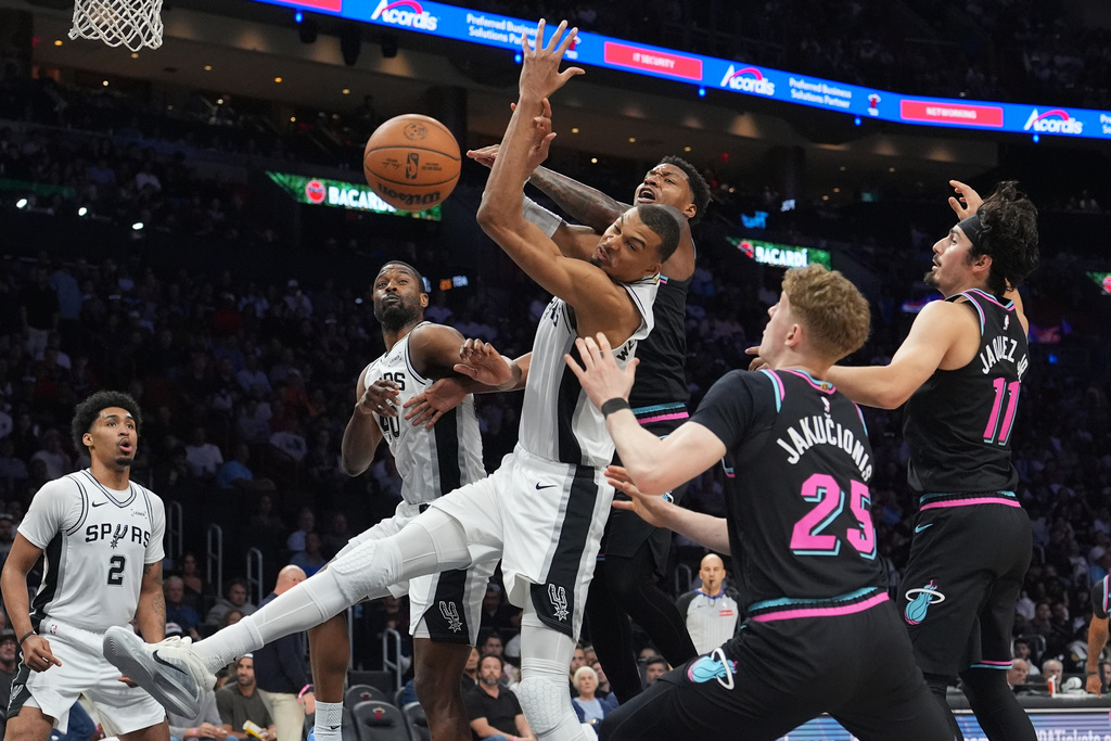 San Antonio Spurs forward Victor Wembanyama, left, front, goes for a rebound against Miami Heat forward Myron Gardner, left, rear, during the second half of an NBA basketball game, Monday, March 23, 2026, in Miami. (AP Photo/Lynne Sladky)