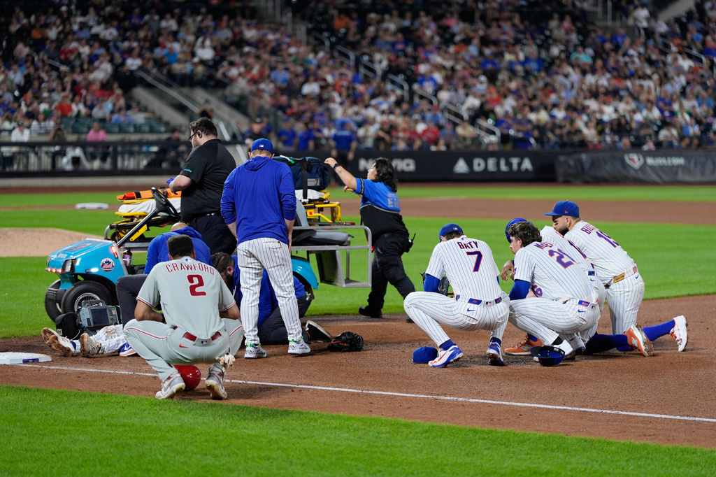 Players looks on as New York Mets first baseman Jared Young is helped bye medical personnel after colliding with pitcher Nolan McLean during the sixth inning of a baseball game against the Philadelphia Phillies, Thursday, Sept. 17, 2026, in New York. (AP Photo/Seth Wenig)