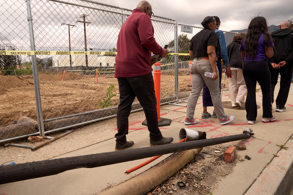 Pastor Jonathan Lewi, left walks past burned pipes next to the site where the Fountain of Life Nazarene Church is being rebuilt, April 26, 2026, in Altadena, Calif. (AP Photo/Damian Dovarganes)