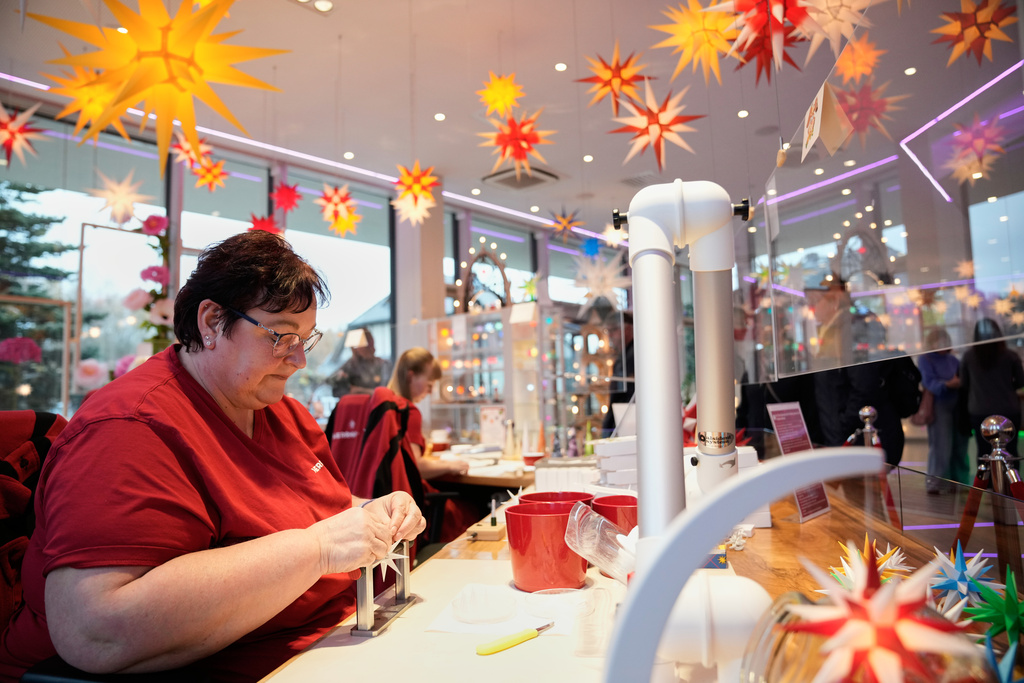 A woman works in the Herrnhuter Sterne GmbH manufacturing, a Christmas stars manufacturing company in Herrnhut, Germany, Nov. 10, 2025. (AP Photo/Ebrahim Noroozi)