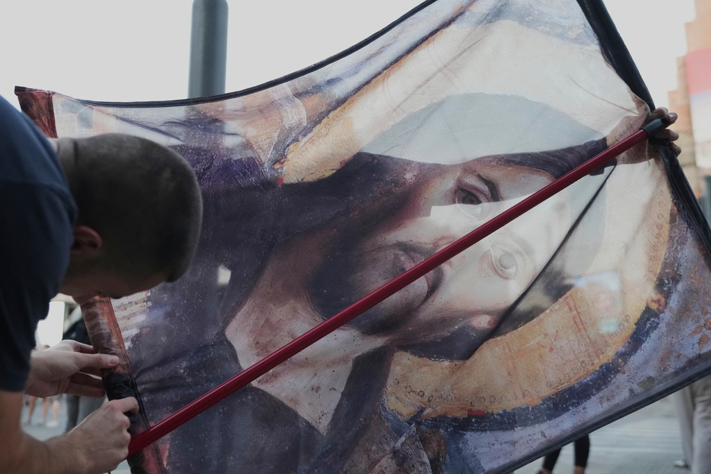 Anti-government protesters prepare a banner featuring the Jesus Christ "Pantocrator" icon, in Belgrade, Serbia, Aug. 14, 2025. (AP Photo/Darko Vojinovic)