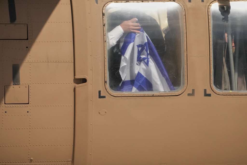A freed Israeli hostage holds an Israeli flag from inside a military helicopter upon arrival at Beilinson Hospital in Petah Tikva, Israel, after being released from Hamas captivity in the Gaza Strip, Monday, Oct. 13, 2025. (AP Photo/Francisco Seco)
