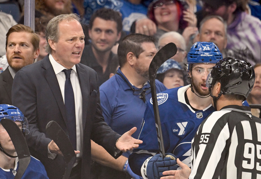 Tampa Bay Lightning head coach Jon Cooper talks with linesman Jonny Murray (95) during the third period of an NHL hockey game against the Nashville Predators, Sunday, March 29, 2026, in Tampa, Fla. (AP Photo/Jason Behnken)