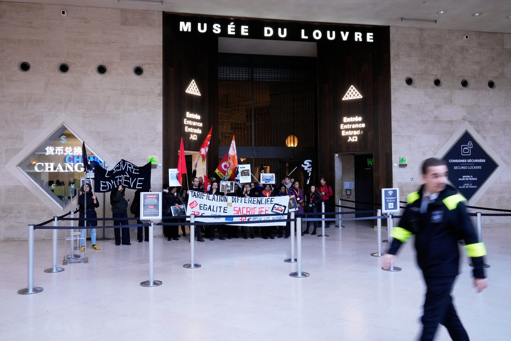 Workers display banners at an entrance of the Louvre museum after they voted to strike for the day over working conditions and other complaints, Monday, Dec. 15, 2025 in Paris. (AP Photo/Michel Euler)