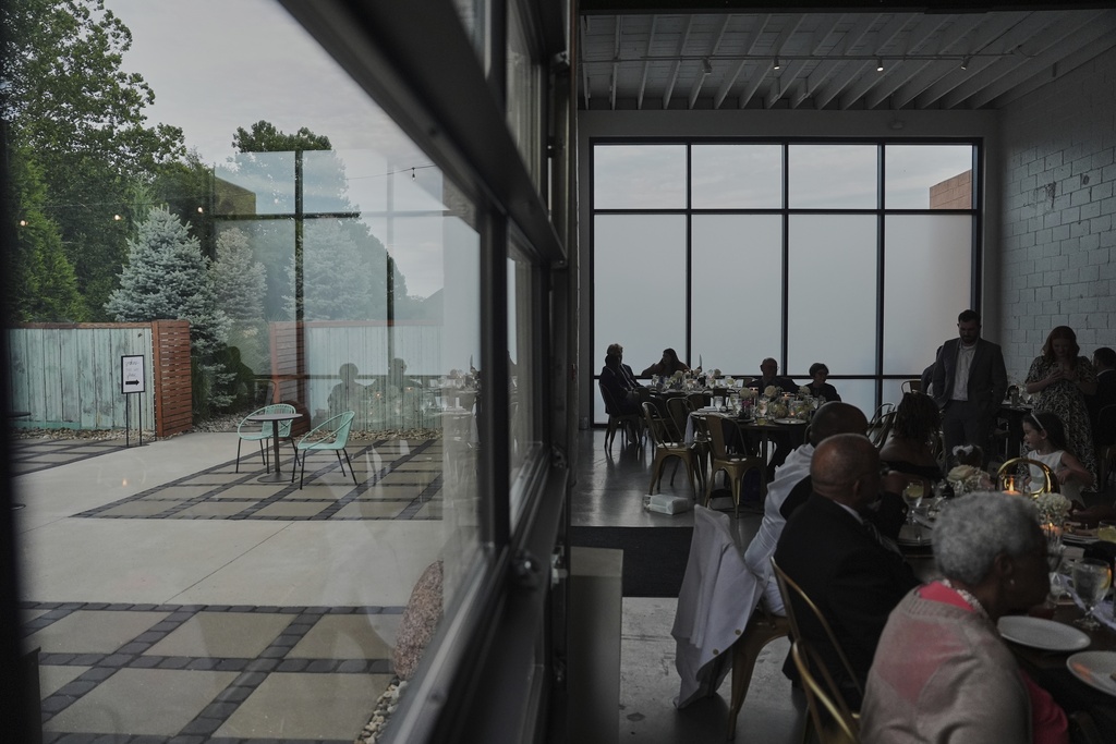 Guests sit inside during cocktail hour as empty chairs sit outside during a wedding Saturday, Aug. 23, 2025, in Newtown, Ohio. (AP Photo/Joshua A. Bickel)