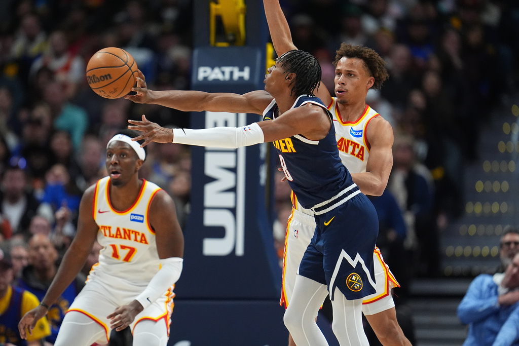 Denver Nuggets guard Peyton Watson, front, passes the ball as Atlanta Hawks guard Dyson Daniels defends in the first half of an NBA basketball game, Friday, Jan. 9, 2026, in Denver. (AP Photo/David Zalubowski)