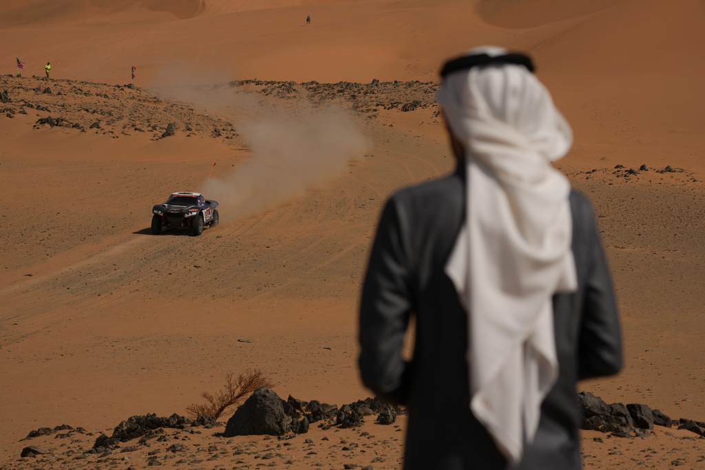 A spectator watches driver Brian Baragwanath and co-driver Leonard Cremer competing during the tenth stage of the Dakar Rally between Wadi Ad Dawasir and Bisha, Saudi Arabia, Wednesday, Jan.14, 2026. (AP Photo/Thibault Camus)