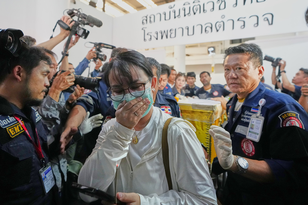 A relative of a victim in a music bar fire leads a coffin containing the victim's body towards a vehicle as it is transferred from a police hospital in Bangkok, Thailand, Tuesday, July 14, 2026. (AP Photo/Sakchai Lalit)