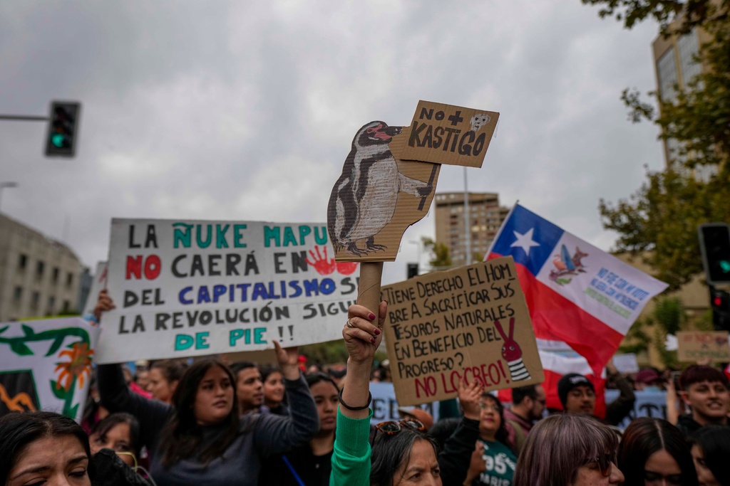 A protester holds a sign that reads in Spanish, "No punishment," a pun involving the name of Chile's President Jose Antonio Kast, during a march marking World Water Day demanding greater environmental protection and animal welfare, in Santiago, Chile, Sunday, March 22, 2026. (AP Photo/Esteban Felix)