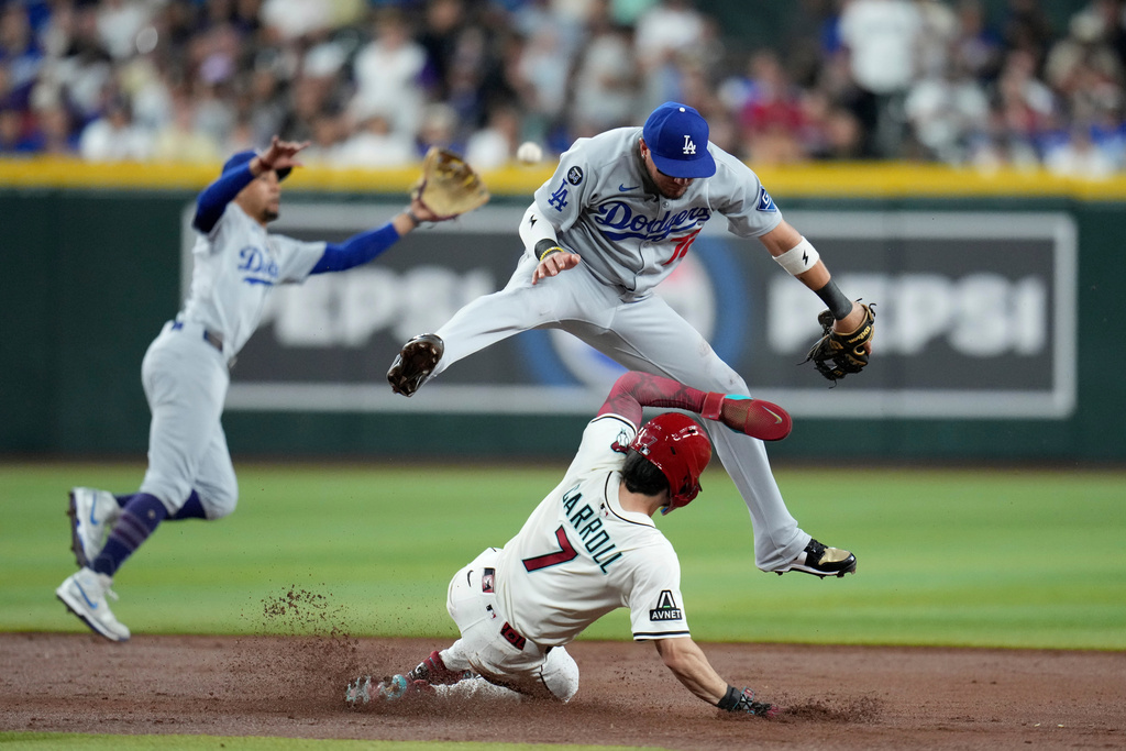 Arizona Diamondbacks' Corbin Carroll (7) steals second base as Dodgers second baseman Miguel Rojas, right, is unable to make a catch on a high throw as Dodgers shortstop Mookie Betts, left, reaches for the ball during the first inning of a baseball game Wednesday, Sept. 24, 2025, in Phoenix. (AP Photo/Ross D. Franklin)