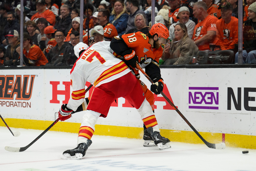 Calgary Flames defenseman Kevin Bahl (7) checks Anaheim Ducks left wing A.J. Greer (18) during the second period of an NHL hockey game, Tuesday, Oct. 13, 2026, in Anaheim, Calif. (AP Photo/Kyusung Gong)