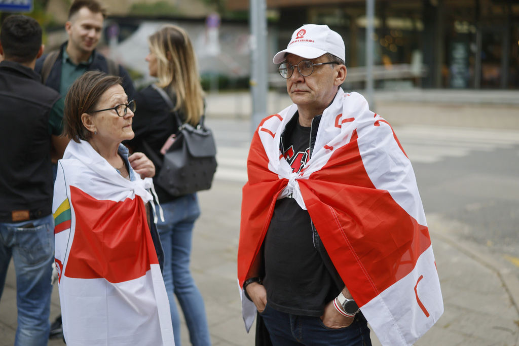 People with old Belarusian flags wait outside the U.S. Embassy in Vilnius, Lithuania, ahead of the arrival of released prisoners from Belarus, Thursday, Sept. 11, 2025. (AP Photo/Mindaugas Kulbis)