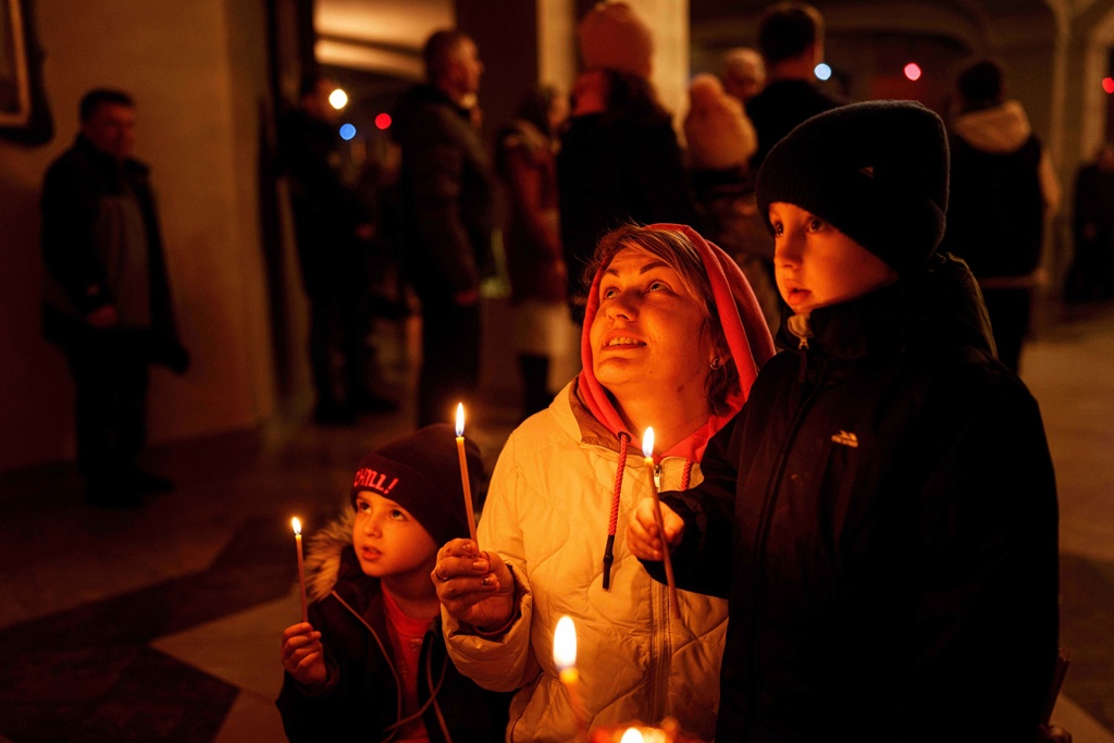 A mother with her children pray during service at the Holy Apostle Andrew church in Bucha, Ukraine, on Sunday, Nov. 23, 2025. (AP Photo/Evgeniy Maloletka)