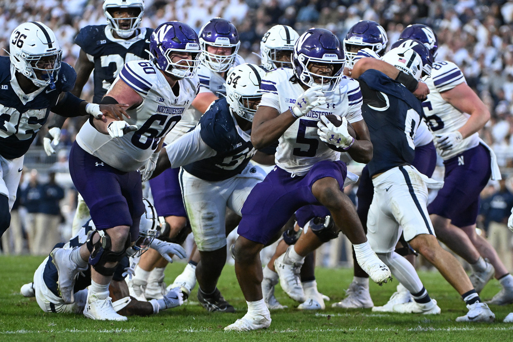 Northwestern running back Caleb Komolafe (5) scores a touchdown in front of Penn State defensive end Zuriah Fisher (36) during the fourth quarter of an NCAA college football game, Saturday, Oct. 11, 2025, in State College, Pa. (AP Photo/Barry Reeger)