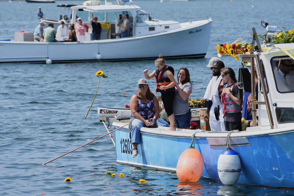 A girl tosses a sunflower into the water in honor of Sunshine Stewart, Sunday, Aug. 10, 2025, in St. George, Maine. (AP Photo/Robert F. Bukaty)