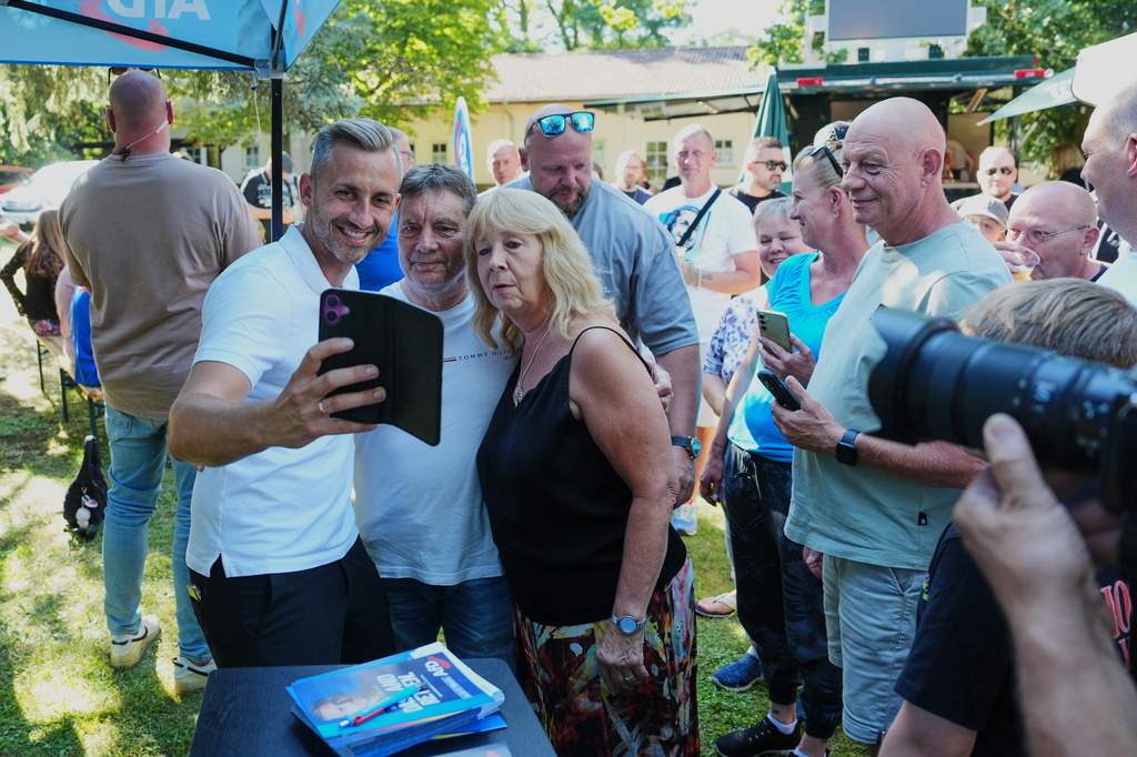 Ulrich Sigmund, the top candidate for the "Alternative for Germany" (AfD) party in the state elections in Saxony-Anhalt, takes photos with supporters at a campaign barbecue hosted by the party in Moeser, Germany, Thursday, Aug. 13, 2026. (AP Photo/Markus Schreiber)