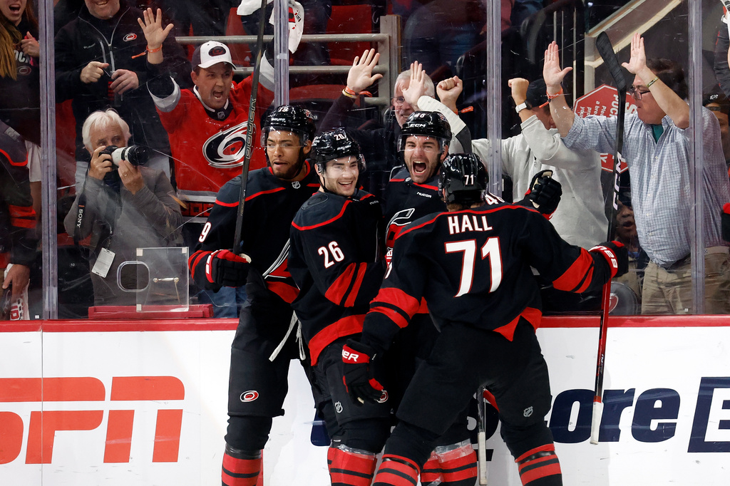Carolina Hurricanes' Jordan Martinook, second from right, celebrates after his winning overtime goal with Sean Walker (26), Taylor Hall (71) and K'andre Miller (19) following the second overtime of Game 2 of an NHL hockey Stanley Cup first-round playoff series against the Ottawa Senators in Raleigh, N.C., Monday, April 20, 2026. (AP Photo/Karl DeBlaker)