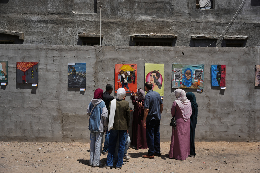 People look at paintings by Palestinian artists during an exhibition in Al-Bureij camp in the central Gaza Strip Tuesday, April 28, 2026. (AP Photo/Abdel Kareem Hana)