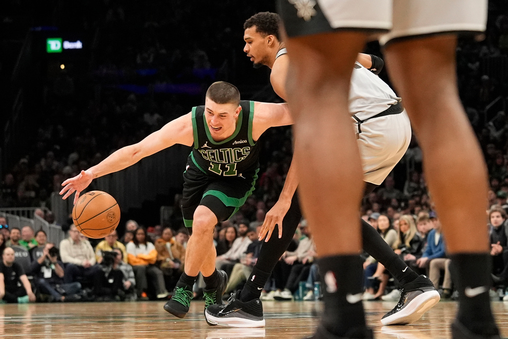 Boston Celtics guard Payton Pritchard goes low to drive by San Antonio Spurs forward Victor Wembanyama during the first half of an NBA basketball game, Saturday, Jan. 10, 2026, in Boston. (AP Photo/Robert F. Bukaty)