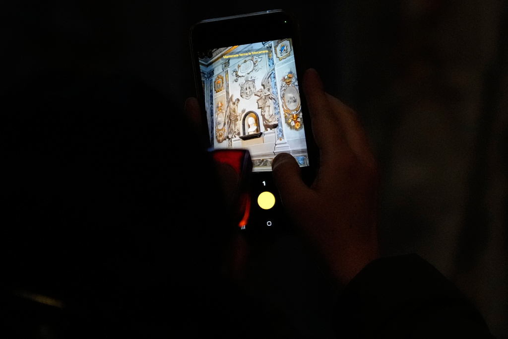 A man takes a picture at a restored fresco to the memory of late Italy's King Umberto II depicting Angels inside the Basilica of St. Lawrence in Lucina in Rome, Sunday, Feb. 1, 2026. (AP Photo/Gregorio Borgia)