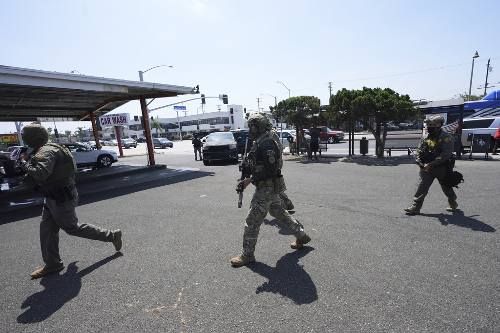 Immigration agents conduct an operation at a car wash on Friday, Aug. 15, 2025, in Montebello, Calif. (AP Photo/Gregory Bull)