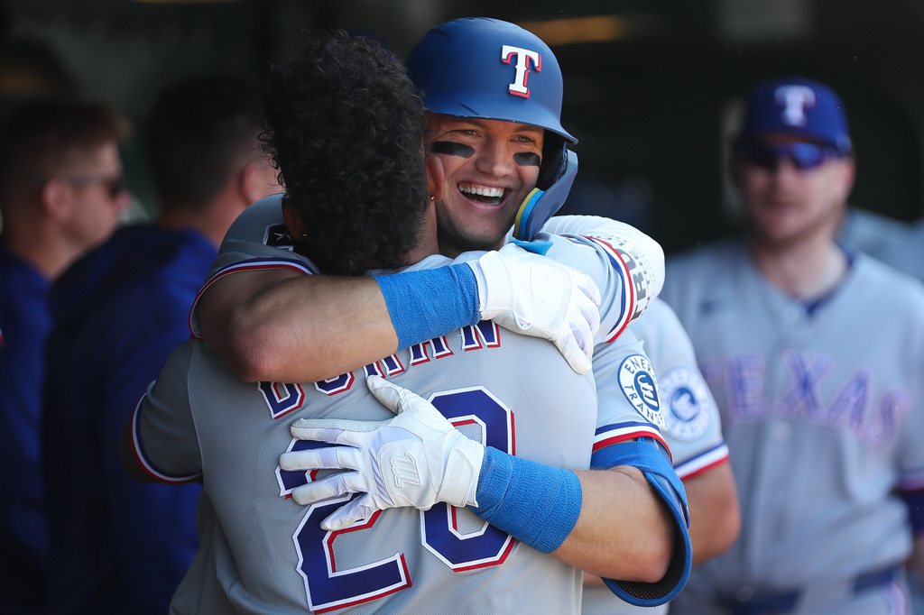 Texas Rangers' Josh Jung, center right, hugs teammate Ezequiel Duran (20) after hitting a two-run home run during the seventh inning of a baseball game against the Athletics, Thursday, April 16, 2026, in West Sacramento, Calif. (AP Photo/Scott Marshall)