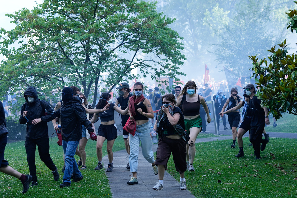 Protesters disperse through a grassy area during a "No G7" demonstration in Geneva, Switzerland, Sunday, June 14, 2026, ahead of the G7 summit scheduled to take place June 15-17. (AP Photo/Laurent Cipriani)