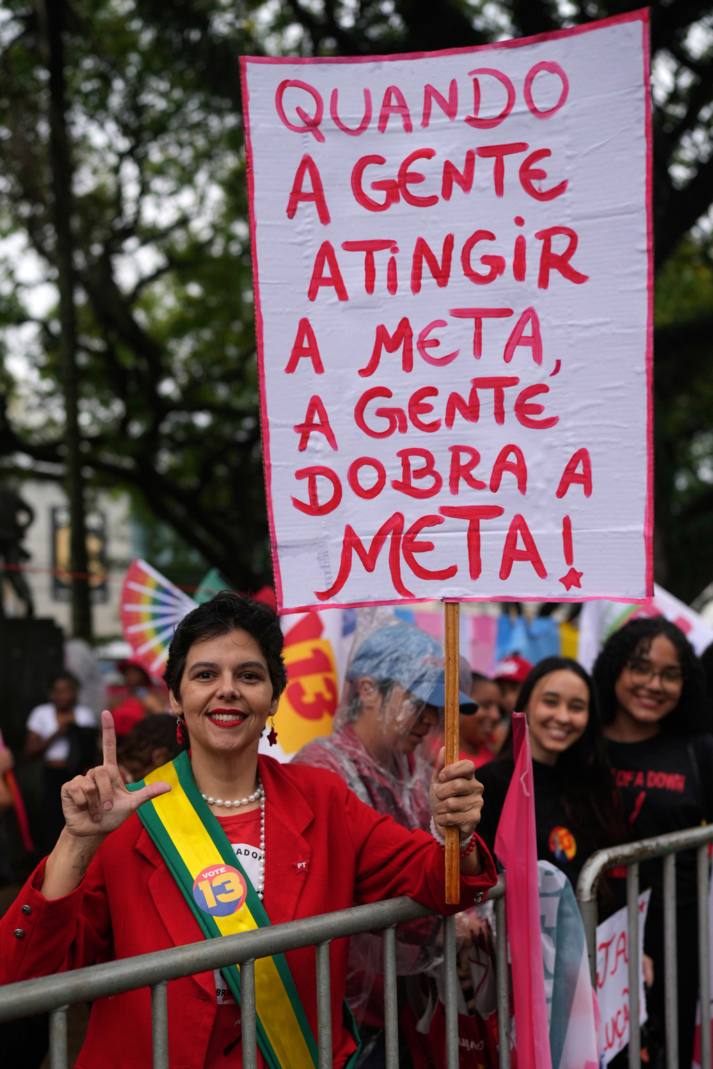 A supporter holds a sign with a message reading in Portuguese, "When we reach the goal, we double the goal," referring to Meta Platforms and concerns about possible election interference, before the arrival of Brazilian President Luiz Inacio Lula da Silva, who is running for reelection, at a campaign rally in Juiz de Fora, Minas Gerais state, Brazil, Friday, Oct. 16, 2026. (AP Photo/Silvia Izquierdo)