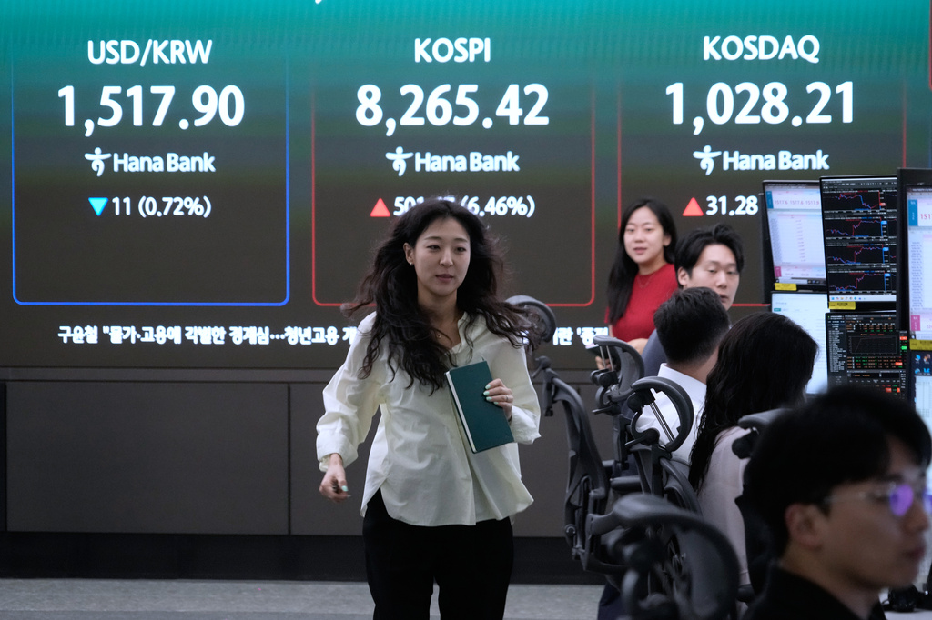 A currency trader passes by a screen showing the Korea Composite Stock Price Index (KOSPI) and the foreign exchange rate between U.S. dollar and South Korean won at the foreign exchange dealing room of the Hana Bank headquarters in Seoul, South Korea, Friday, June 12, 2026. (AP Photo/Ahn Young-joon)