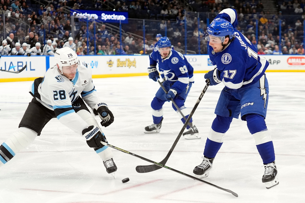 Tampa Bay Lightning center Dominic James (17) sends a pass to center Gage Goncalves (93) around Utah Mammoth defenseman Ian Cole (28) during the second period of an NHL hockey game Monday, Jan. 26, 2026, in Tampa, Fla. (AP Photo/Chris O'Meara)