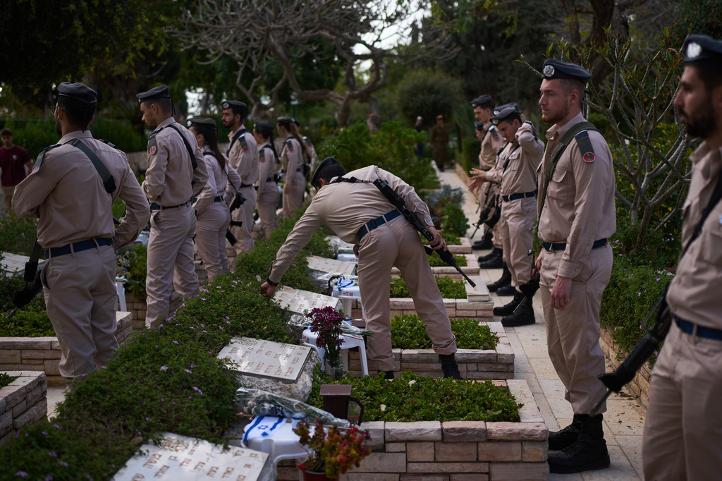 Israeli soldiers place flags and flowers on graves at a military cemetery ahead of the annual Memorial Day honoring fallen soldiers and victims of nationalistic attacks in Tel Aviv, Israel, Monday, April 20, 2026. (AP Photo/Oded Balilty)