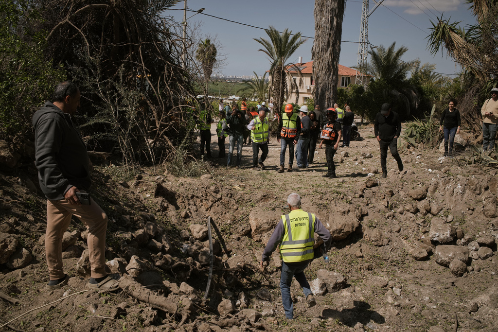 Residents and Israeli security forces inspect the site struck by an Iranian missile in central Israel, Thursday, March 5, 2026. (AP Photo/Leo Correa)
