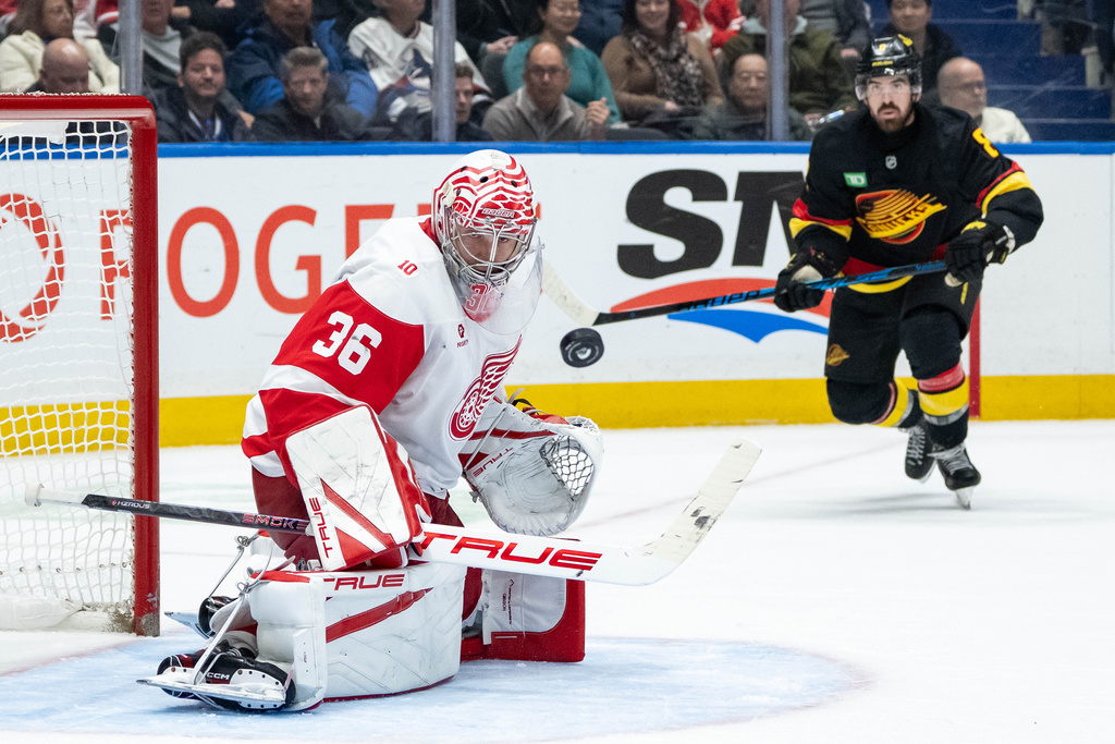 Detroit Red Wings goaltender John Gibson (36) and Vancouver Canucks' Conor Garland (8) watch the puck during the third period of an NHL hockey game in Vancouver, B.C., Monday, Dec. 8, 2025. (Ethan Cairns/The Canadian Press via AP)