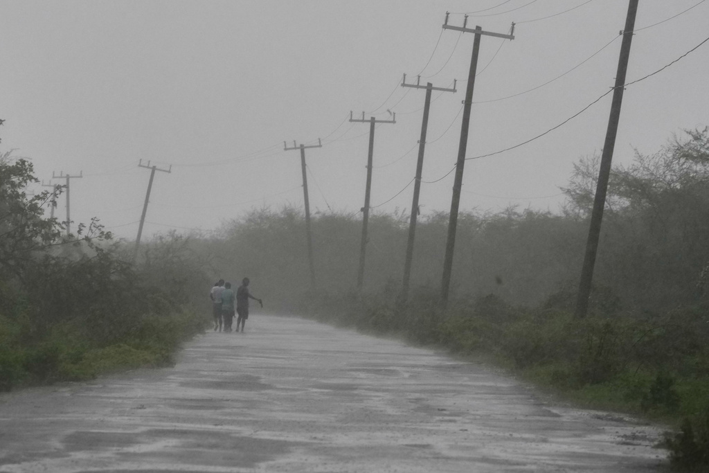 People walk along a road during the passing of Hurricane Melissa in Rocky Point, Jamaica, Tuesday, Oct. 28, 2025. (AP Photo/Matias Delacroix)