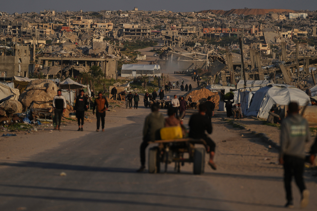 Palestinians walk along a street surrounded by buildings destroyed during Israeli air and ground operations in Khan Younis, southern Gaza Strip, Thursday, April 9, 2026. (AP Photo/Abdel Kareem Hana)