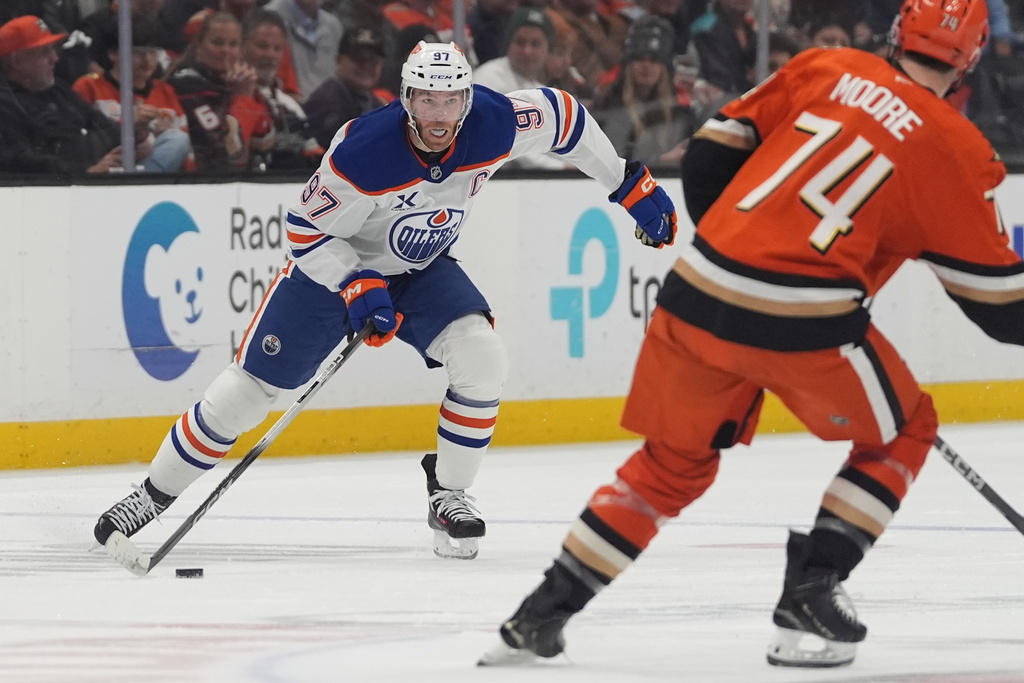 Edmonton Oilers center Connor McDavid, left, looks to pass as Anaheim Ducks defenseman Ian Moore defends during the second period of an NHL hockey game Wednesday, Feb. 25, 2026, in Anaheim, Calif. (AP Photo/Gregory Bull)