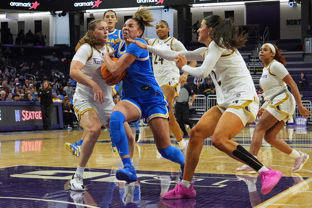 UCLA guard Kiki Rice, center, drives to the basket against Northwestern guard Tate Lash, left, and guard Casey Harter during the first half of an NCAA college basketball game in Evanston, Ill., Sunday, Jan. 25, 2026. (AP Photo/Nam Y. Huh)