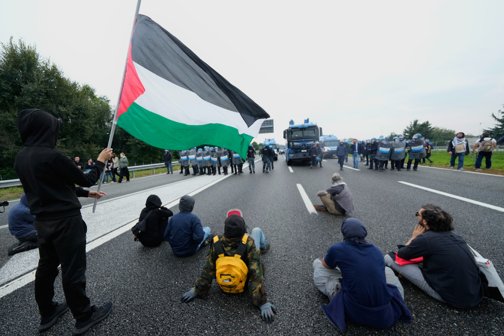 Pro-Palestinian demonstrators sits on the Milan's ring road during a protest part of a national general strike called by different unions to protest against the situation in Gaza two days after Israeli forces intercepted a Gaza-bound aid flotilla in the Mediterranean Sea, in Milan, Italy, Friday, Oct. 3, 2025. (AP Photo/Luca Bruno)
